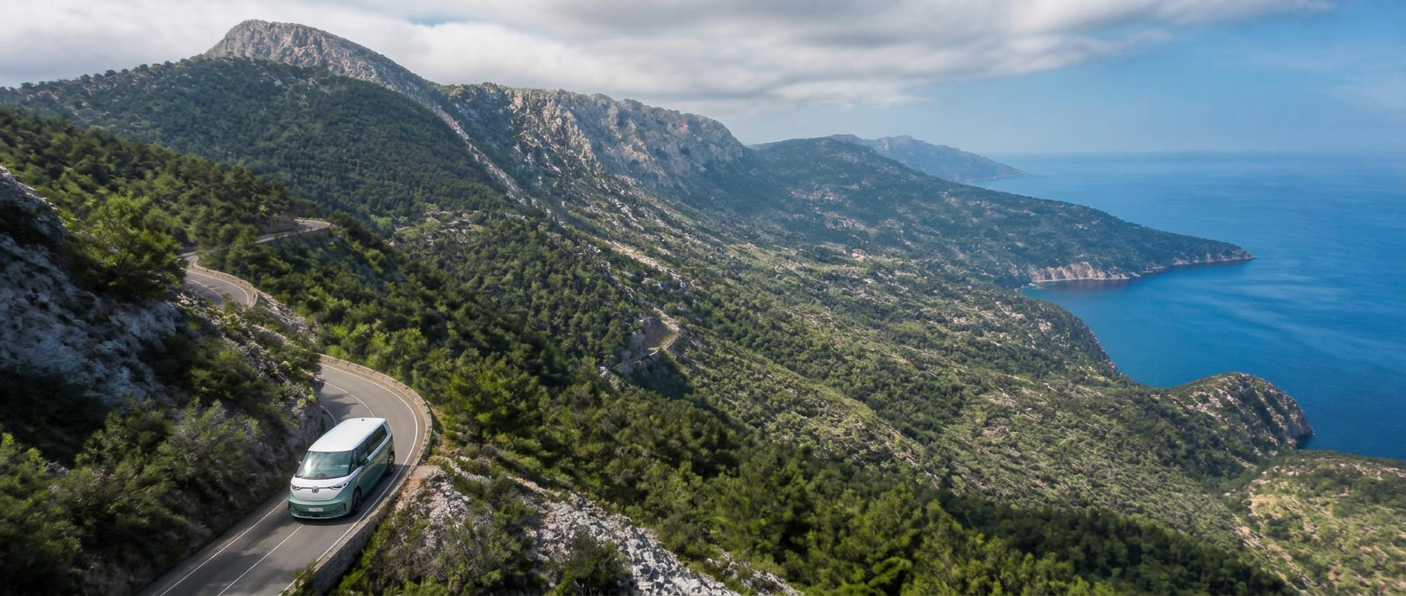 Volkswagen ID Buzz circulando por una carretera de montaña serpenteante en la Serra de Tramuntana de Mallorca vista desde el aire